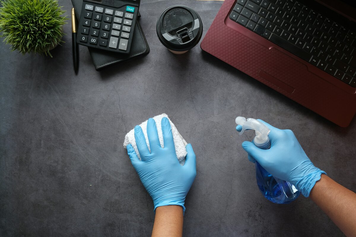 Pulizia professionale di ufficio con detergente su scrivania